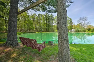 a park bench sitting in front of a lake at The Red Pine Cabin with Private Pond and Dock! in Loudonville