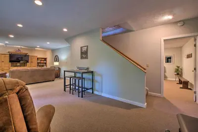 a living room with a staircase and a table and chairs at The Red Pine Cabin with Private Pond and Dock! in Loudonville