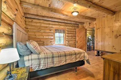 a bedroom with a bed in a log cabin at The Red Pine Cabin with Private Pond and Dock! in Loudonville