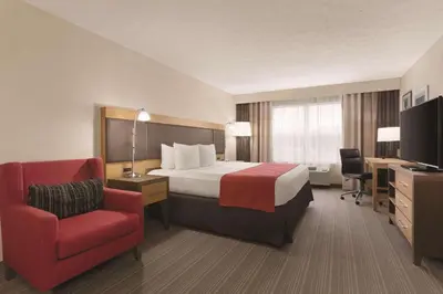 a hotel room with a bed and a red chair at Country Inn & Suites by Radisson, Fairborn South, OH in Fairborn