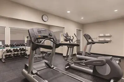 a gym with two tread machines and a clock at Country Inn & Suites by Radisson, Fairborn South, OH in Fairborn