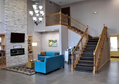 a living room with a staircase and a blue couch at Country Inn & Suites by Radisson, Fairborn South, OH in Fairborn