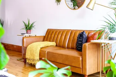 a brown couch in a living room with plants at Jungle House Luxury Homes - Columbus Downtown Short North - Walk to Convention Center & Nationwide Arena - Sleeps up to 10 - Free Parking - Over 5,800 Five Stars in Columbus