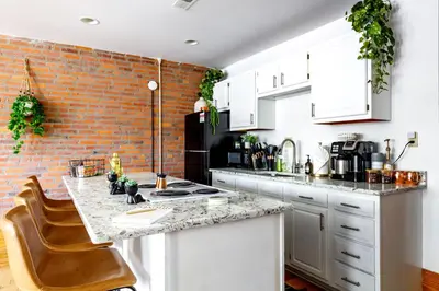 a kitchen with white cabinets and a brick wall at Jungle House Luxury Homes - Columbus Downtown Short North - Walk to Convention Center & Nationwide Arena - Sleeps up to 10 - Free Parking - Over 5,800 Five Stars in Columbus