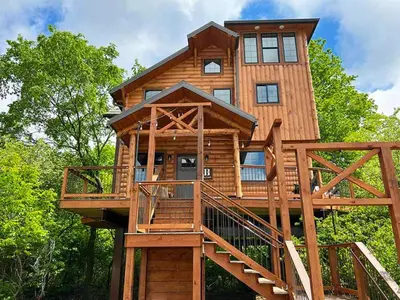 a tree house with a deck and stairs at Skyview Treehouse by Amish Country Lodging in Millersburg
