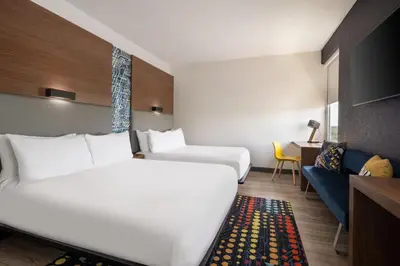 a hotel room with two beds and a couch at Aloft Beachwood in Beachwood