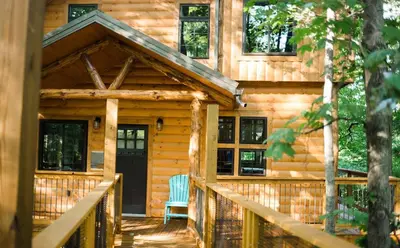 a log cabin with a porch and a door at Skyview Treehouse A by Amish Country Lodging in Millersburg