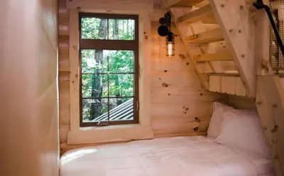 a bed in a tiny house with a window at Skyview Treehouse A by Amish Country Lodging in Millersburg