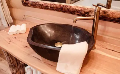 a black sink on a wooden counter with a paper towel at Skyview Treehouse A by Amish Country Lodging in Millersburg