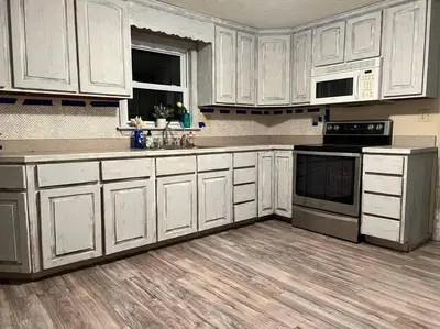 a kitchen with white cabinets and a wooden floor at Cottage near Cedar Point and downtown Sandusky in Sandusky