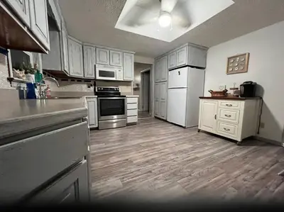a large kitchen with white appliances and wooden floors at Cottage near Cedar Point and downtown Sandusky in Sandusky
