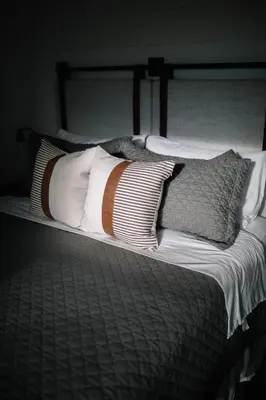a bed with white pillows and a black and white comforter at Cozy Cottage on 250 Acre Dairy Farm Near Ark in Dry Ridge
