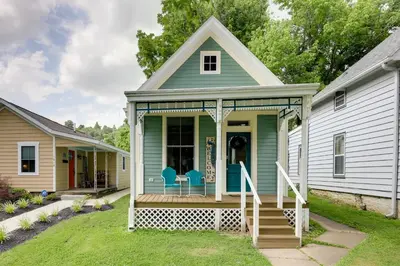 a green house with two blue chairs on a porch at Historic Madison Retreat - 1 Mi to Ohio River in Madison