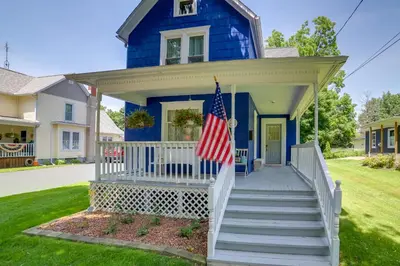 a blue house with an american flag on the front porch at BBQ, Fire Pit and Yard Family Home in Adrian in Adrian