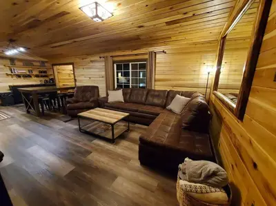 a living room with a couch and a table in a cabin at Luxury Cabin w/ Game Room & Hot Tub at Cave Run Lake in Wellington