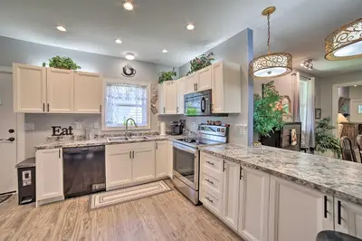a kitchen with white cabinets and a large counter top at Spacious Fort Wayne Condo with Porch and Storage! in Fort Wayne