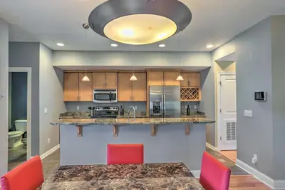 a kitchen with a table and red chairs at Central Cleveland Gem with Direct Skyline View! in Cleveland