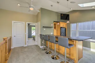 a kitchen with a bar with chairs and a tv at Central Cleveland Gem with Direct Skyline View! in Cleveland