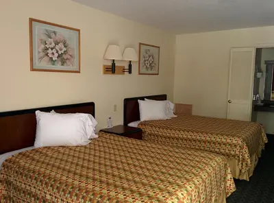a hotel room with two beds with orange sheets at Economy Inn Toledo-Perrysburg in Perrysburg