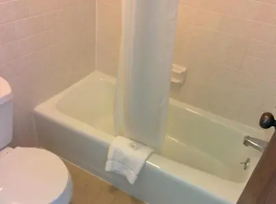 a bathroom with a white toilet and a tub and a sink at Economy Inn Toledo-Perrysburg in Perrysburg