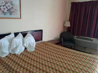 a hotel room with a bed with pillows and a chair at Economy Inn Toledo-Perrysburg in Perrysburg