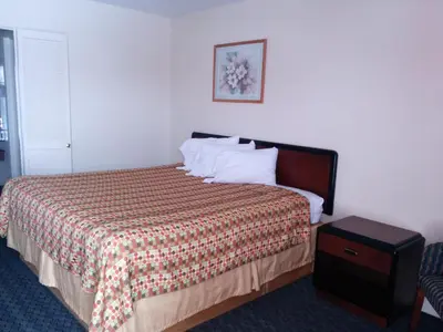a bedroom with a bed with a comforter and a table at Economy Inn Toledo-Perrysburg in Perrysburg