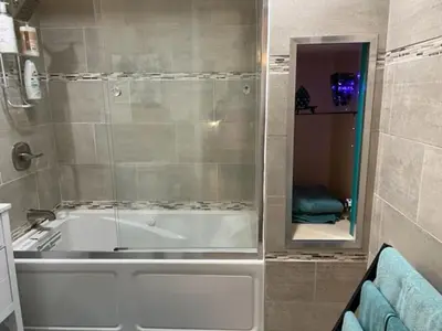 a bathroom with a tub and a shower with a mirror at Uber Close to Ohio City, Cleveland (Lower) in Cleveland