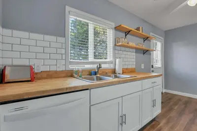a kitchen with white cabinets and a sink at Housepitality - The Sunset House in Columbus