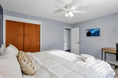 a bedroom with a white bed with a ceiling fan at Housepitality - The Sunset House in Columbus