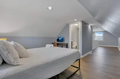 a bedroom with a large white bed and a desk at Housepitality - The Sunset House in Columbus
