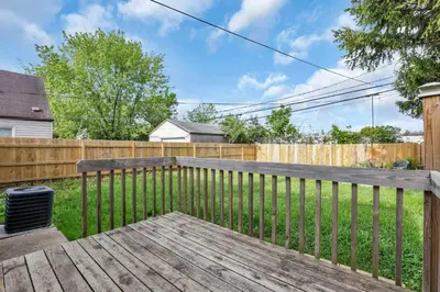 a wooden bench in a backyard with a fence at Housepitality - The Sunset House in Columbus