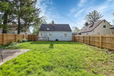 a backyard with a fence and a white house at Housepitality - The Sunset House in Columbus