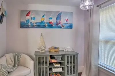a room with a chair and a table with sailboats on the wall at Lorain Lake Cottage Less Than 1 Mi to Lake Erie Fun! in Lorain