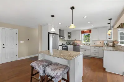 a kitchen with white cabinets and a island with bar stools at Serene 6BR country home on 325 acres ATV for rent in Burgettstown