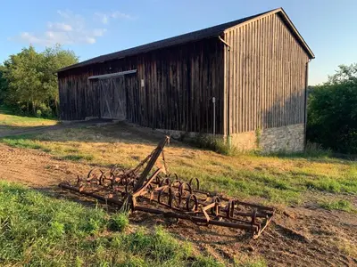 a pile of wood in front of a barn at Serene 6BR country home on 325 acres ATV for rent in Burgettstown