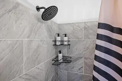 a bathroom with a shower with gray tiles at Center of Little Italy #2 in Cleveland