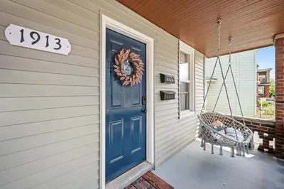 a porch with a blue door and a swing at Center of Little Italy #2 in Cleveland