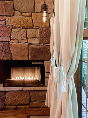 a stone wall with a fireplace in a room at Cricket Hill Treehouse by Amish Country Lodging in Millersburg