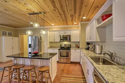 a kitchen with white cabinets and a island with bar stools at Cheerful Tiffin Digs in the Heart of Downtown in Tiffin