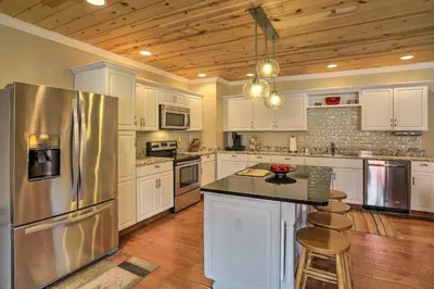 a kitchen with white cabinets and a stainless steel refrigerator at Cheerful Tiffin Digs in the Heart of Downtown in Tiffin