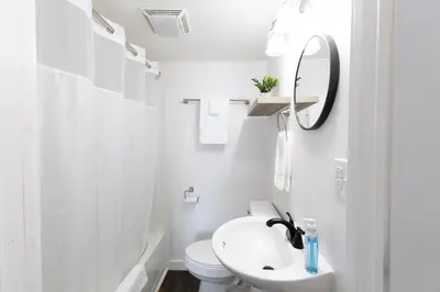 a white bathroom with a sink and a mirror at Anchor Bay Inn and Suites in Sandusky