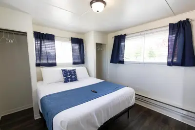 a bedroom with a bed with a blue blanket and a window at Anchor Bay Inn and Suites in Sandusky
