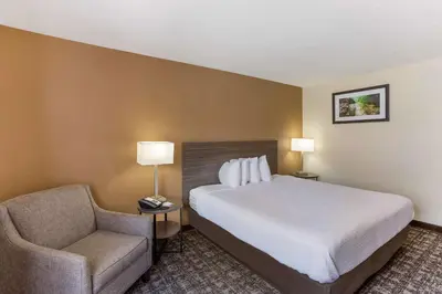 a hotel room with a bed and a chair at Best Western Logan Inn in Chapmanville