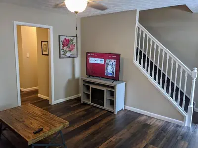 a living room with a flat screen tv and a staircase at Carter #5 Two bedroom unit near Xavier Downtown in Cincinnati