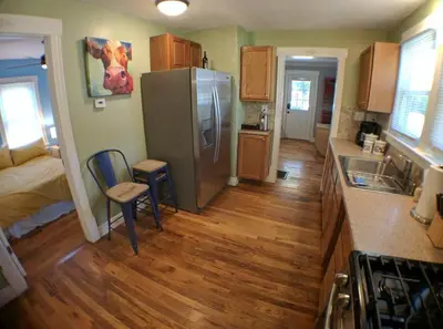 a kitchen with a stainless steel refrigerator and wooden floors at Harper Two Bedroom House in Historic Loveland in Loveland