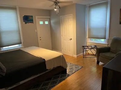 a bedroom with a bed and a chair and windows at Main, Three Bedroom House in Historic Loveland in Loveland