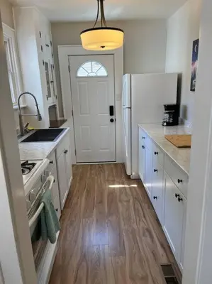 a kitchen with a white refrigerator and a wooden floor at Warren 1 Bedroom Unit near Xavier Downtown in Bellevue