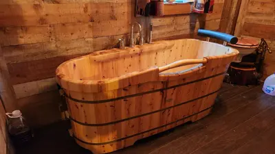 a wooden bath tub with a sink in a room at River Log Cabins in Waterville