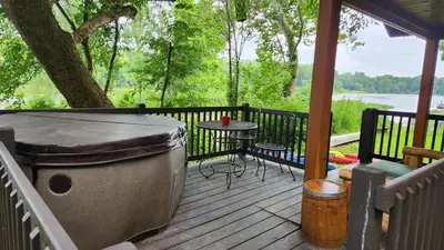 a wooden deck with a grill and a table on it at River Log Cabins in Waterville