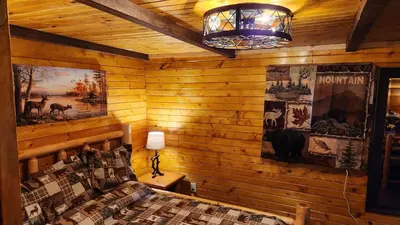 a bedroom with a wooden wall with a bed and a lamp at River Log Cabins in Waterville